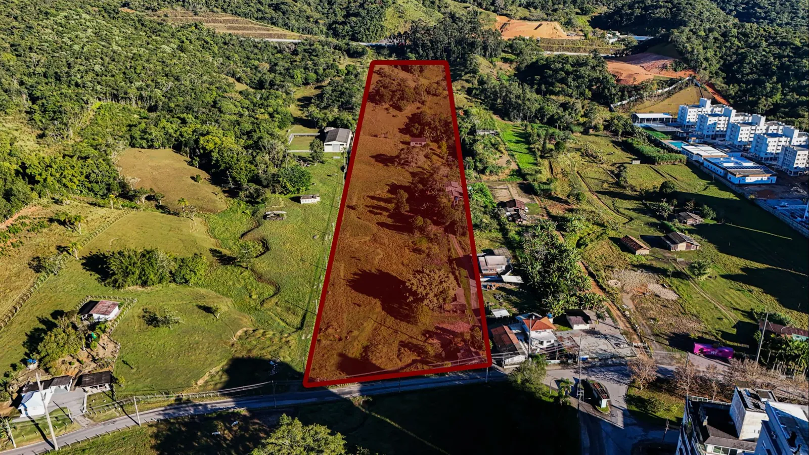 Vista aérea do terreno do Mirante Garden Club demarcado em vermelho, cercado de verde, na Pedra Branca