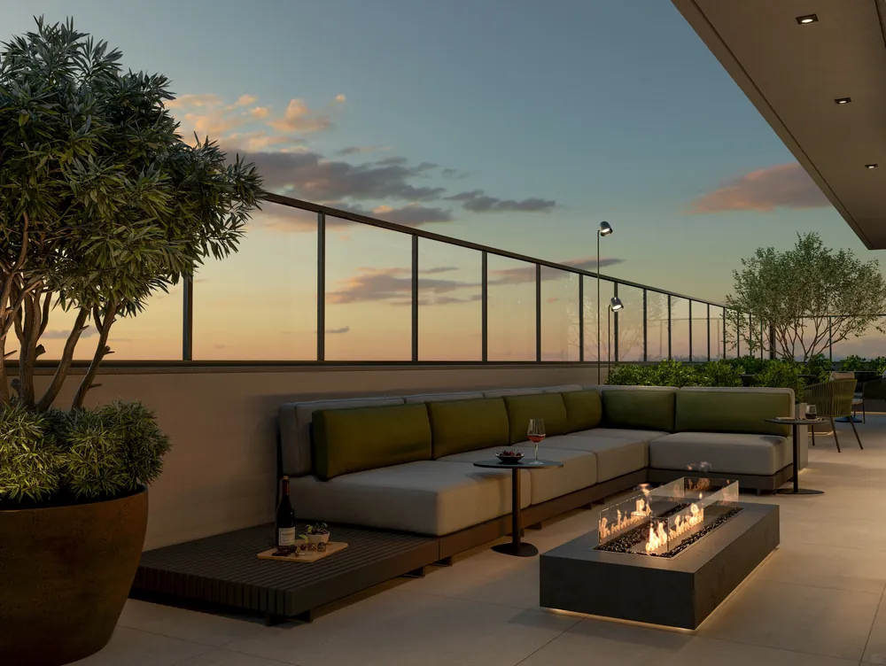 Praça de fogo do New York Residence ao entardecer, com lareira a gás, sofá em L e guarda-corpo de vidro