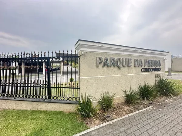 Muro da entrada com o letreiro Parque da Pedra Condomínio e o gradil ao lado