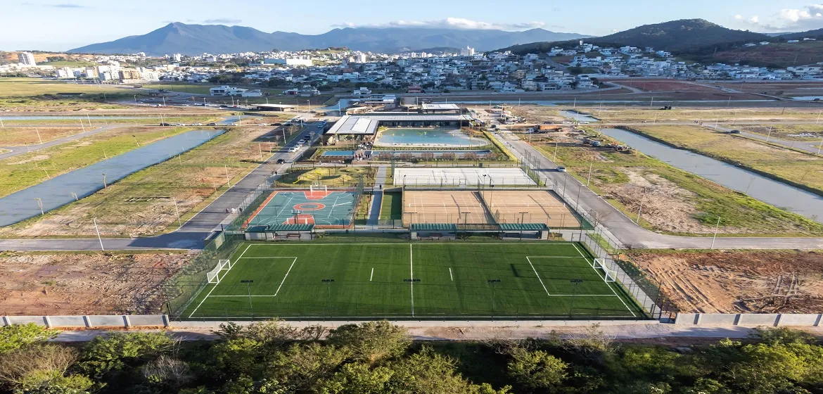 Foto aérea do clube, das quadras de tênis e beach tennis e do campo de futebol, com os canais do condomínio em volta