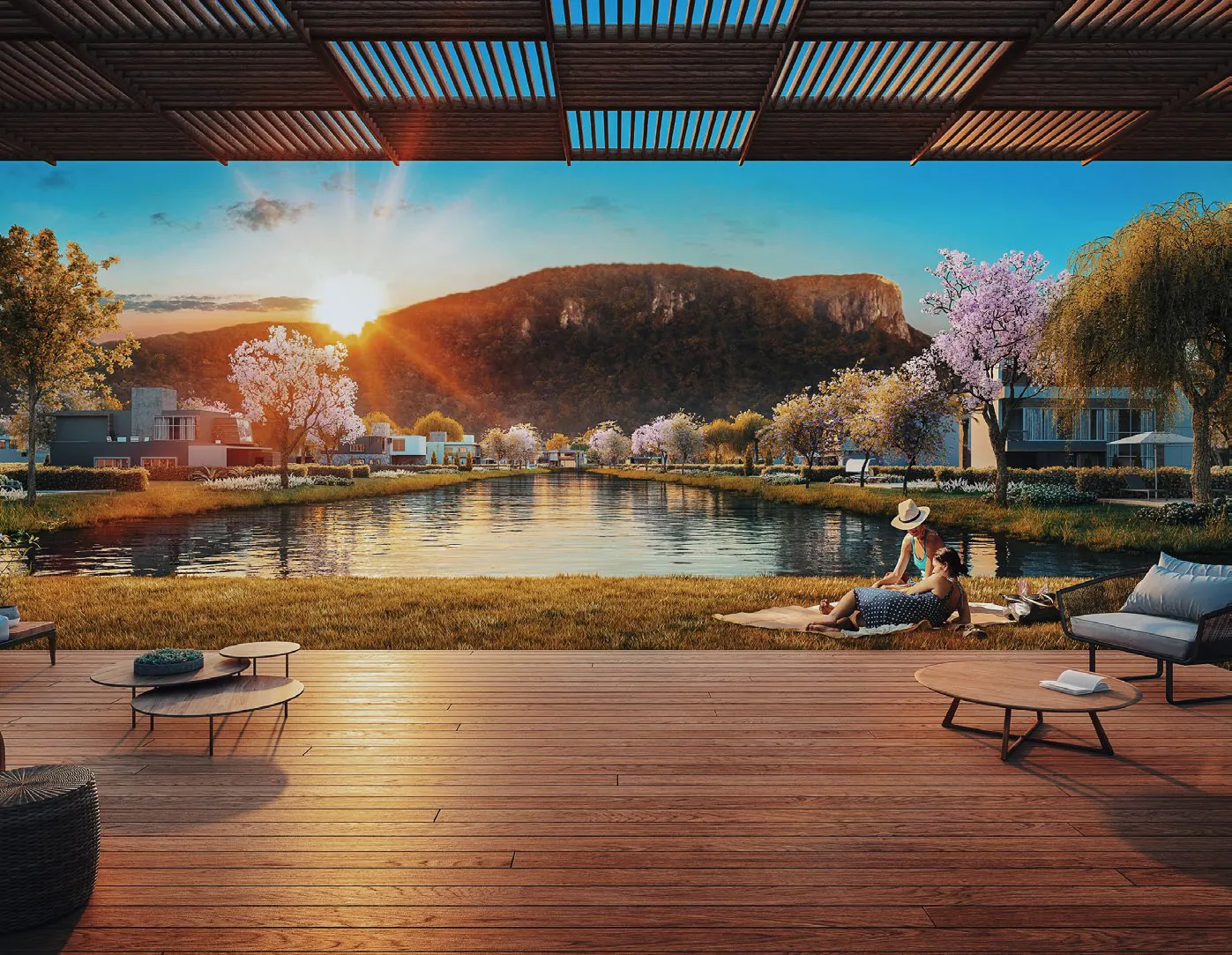 Deck de madeira com poltronas à beira de um dos lagos do Reserva da Pedra, com ipês floridos e o morro da Pedra Branca ao pôr do sol