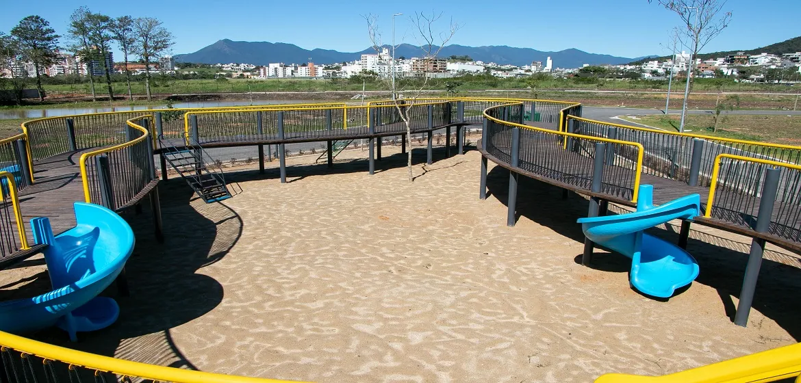 Playground suspenso Reserva da Aventura, com passarela de madeira em circuito e escorregadores azuis sobre a areia